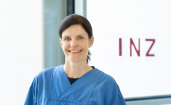 Frau mit dunklen Haaren vor hellem Hintergrund